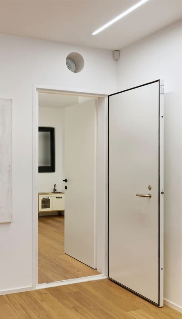 דלת ממ"ד לבנה פתוחה לחלל מואר עם רצפה עץ בהירה